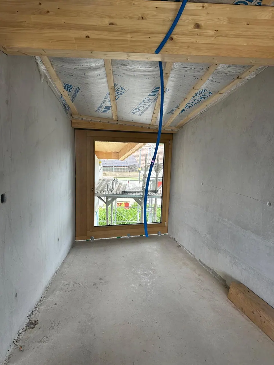 Fenêtre aspect bois posée dans une pièce en construction